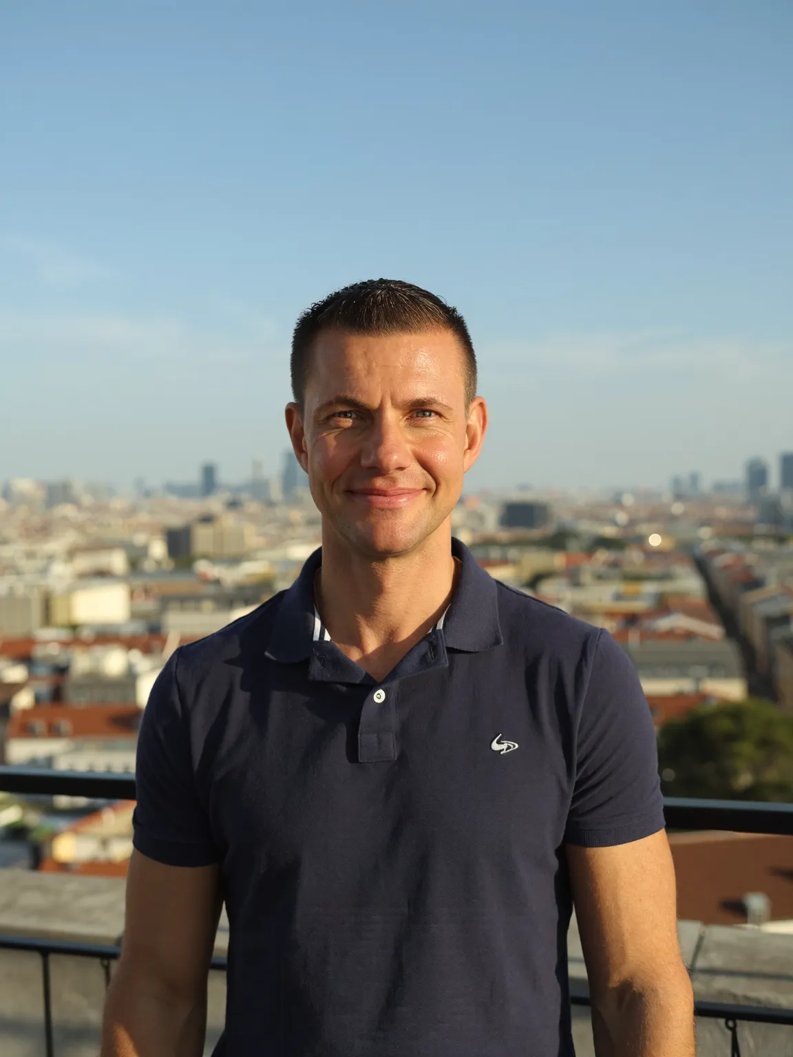 Matthias Neumann lächelnd auf einer Dachterrasse im Abendlicht