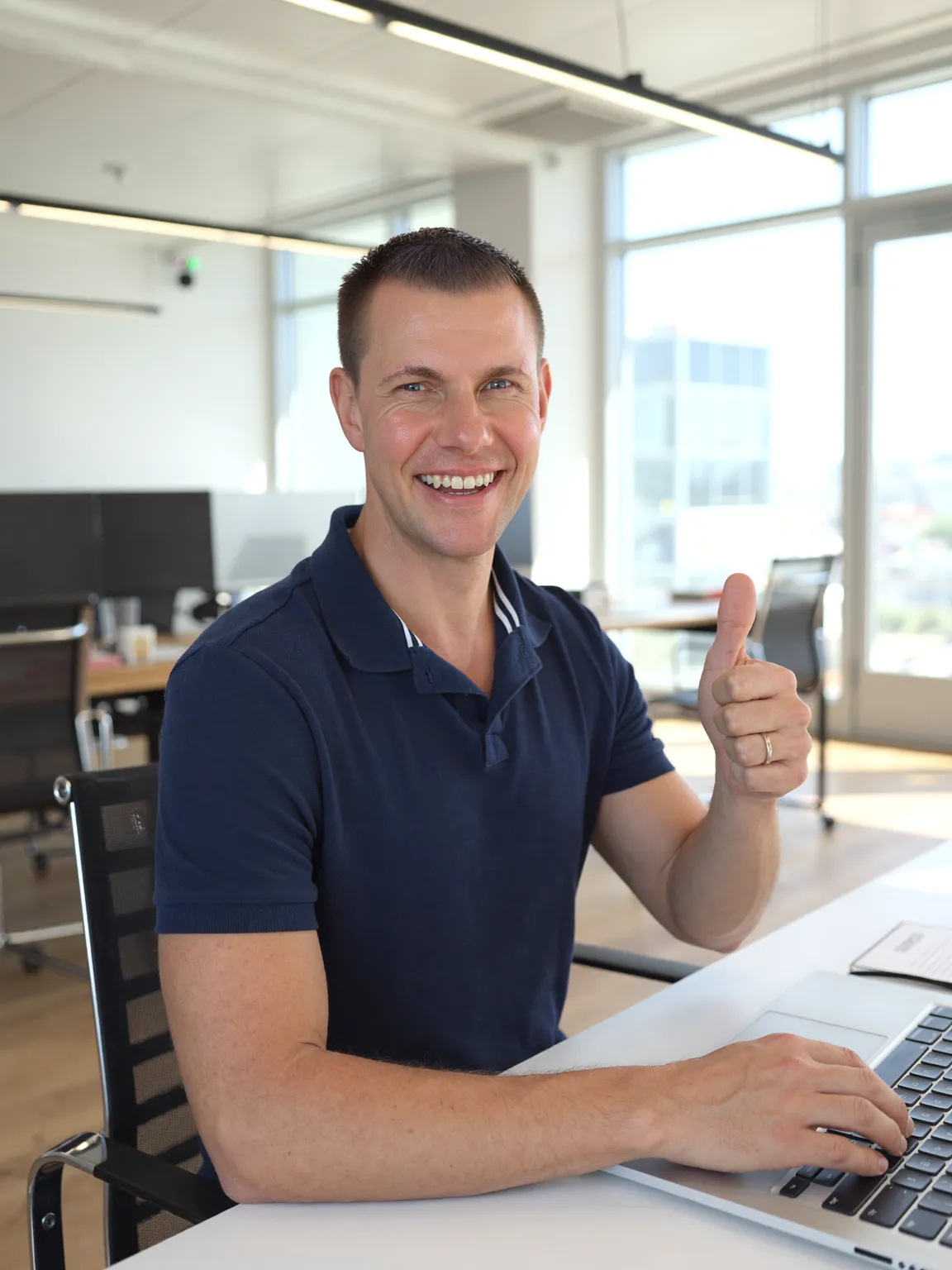 Matthias Neumann am Laptop, lachend mit Daumen hoch